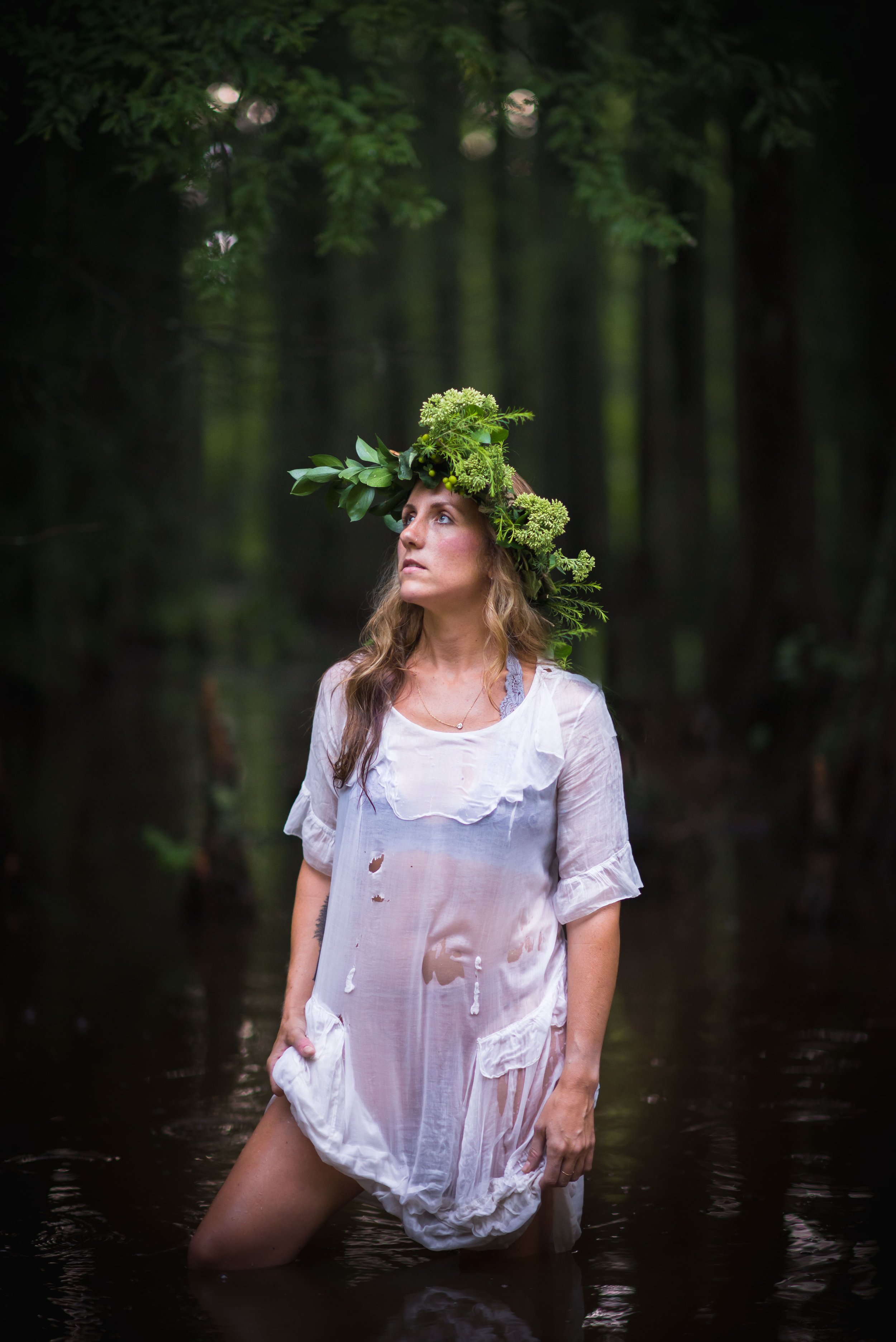 woman standing in a marsh wearing a nature crown and sheer antique white dress 