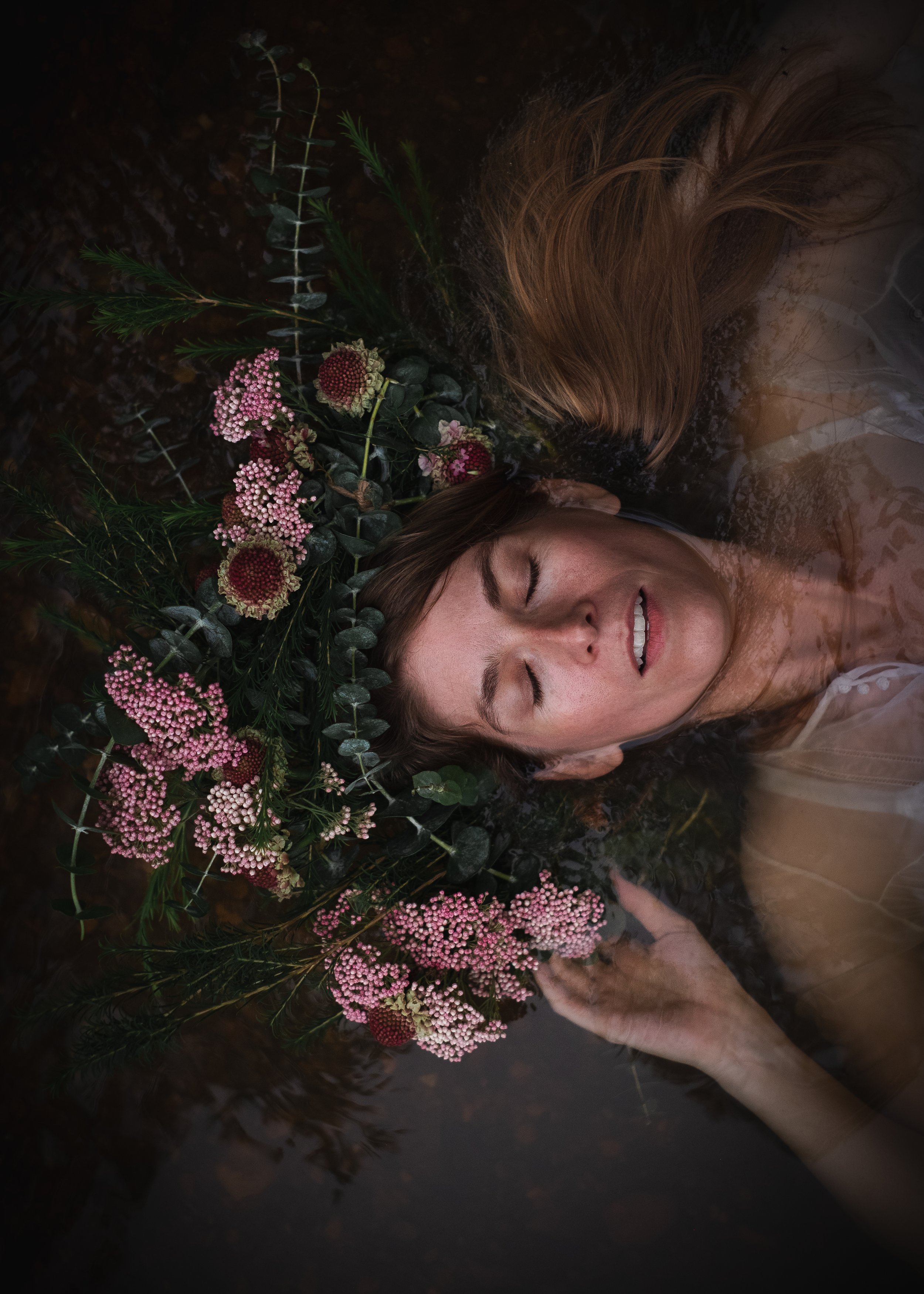 woman wearing a pink and green nature crown floating in water