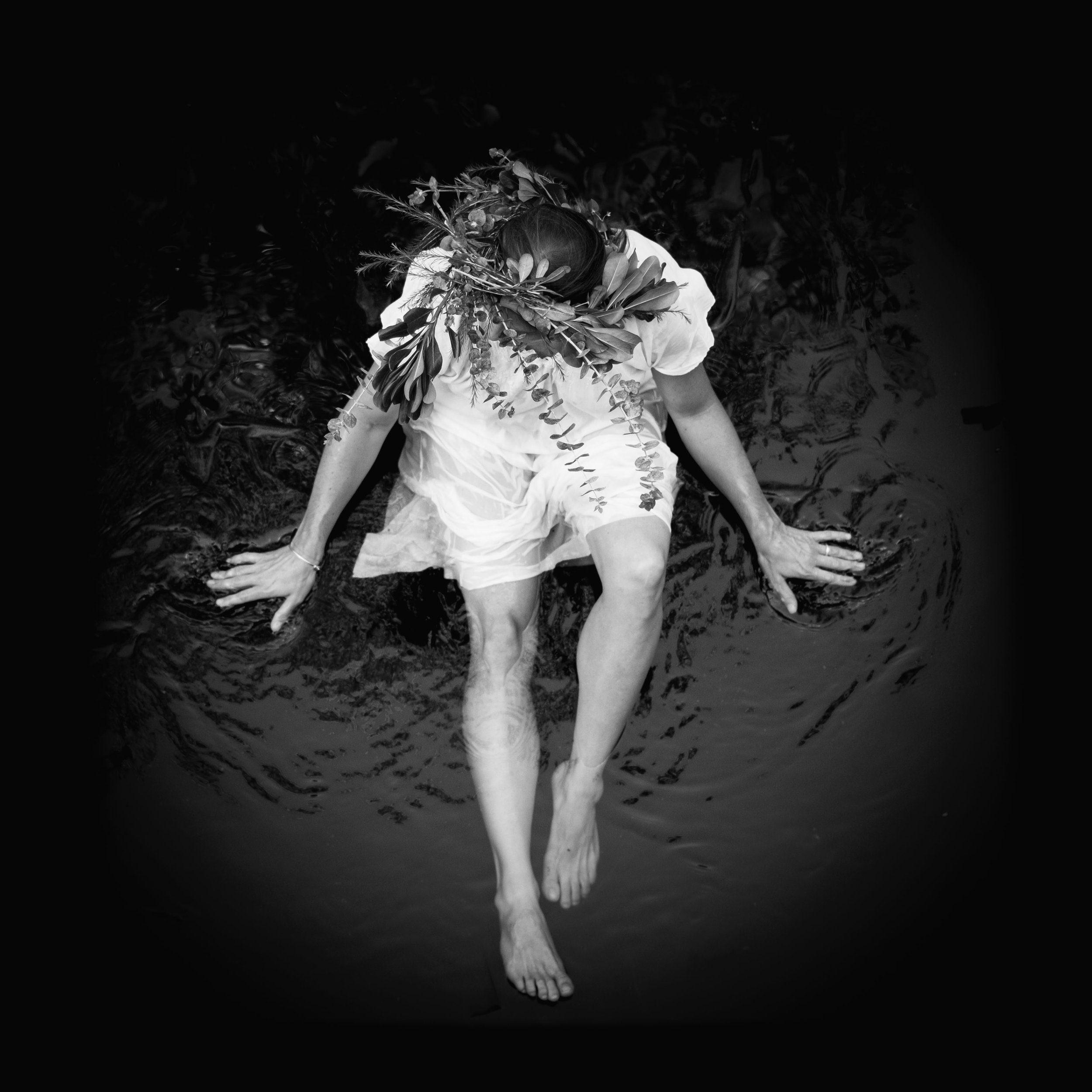 black and white top down of woman wearing nature crown in water 