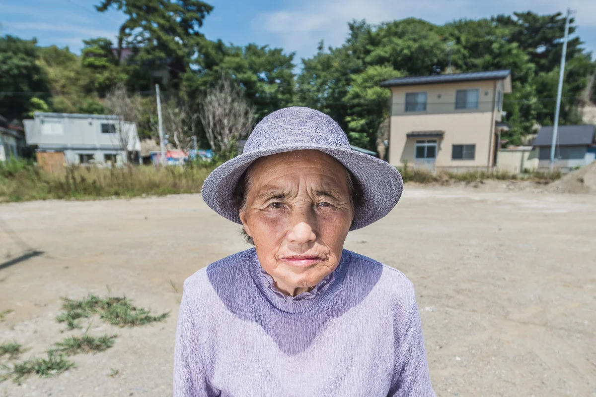  Hatsamu Suzuki, 86, Nonoshima Island, rapeseed  Hatsumu stands in front of the location of her previous home that was swept away during the tsunami. She grew up on Nonoshima Island, farming for 70 years.&nbsp;She has three children, all of whom live