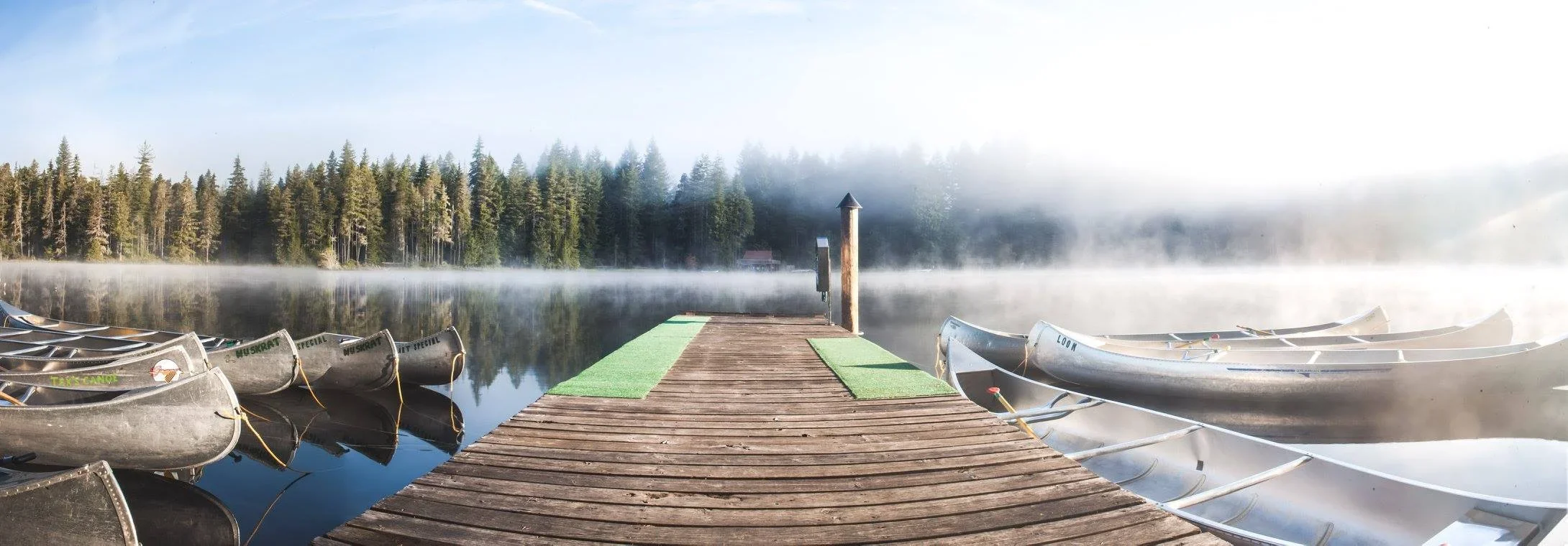 trail-and-sail-community-camp-Lake-Bennettsen-totem-landing-dock-metal-canoes-sunrise-tayler-berard-creative.webp