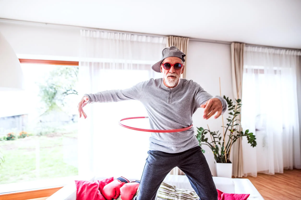 Dance Your Way Back to Youthfulness. Senior man having fun at home hoola hooping. Dancing your way back to youthfullness