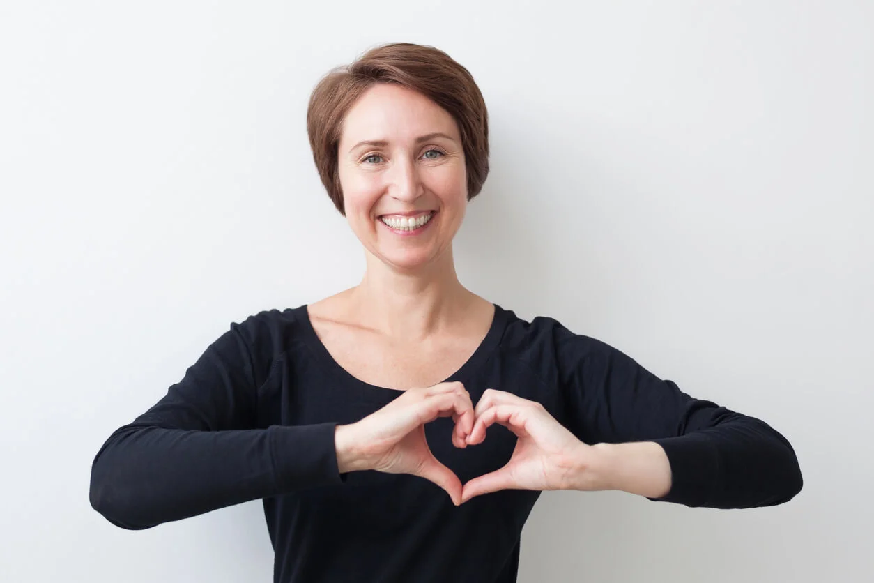Take care of your health Woman in a ballroom dance studio making a heart shape with her hands