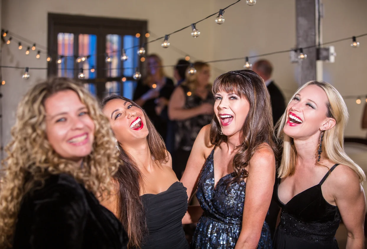 Four mature women laughing loudly at a party