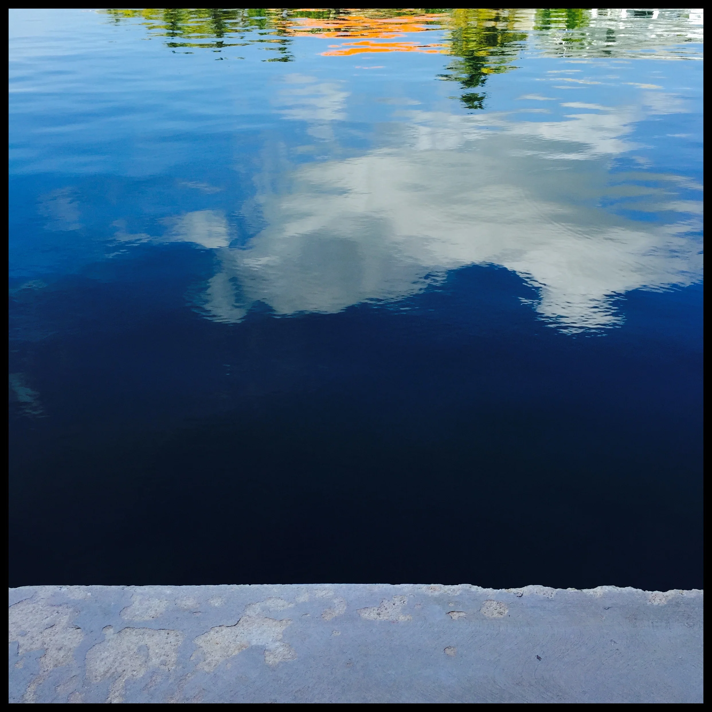 At dock's edge: roof, leaves, sky, reflected