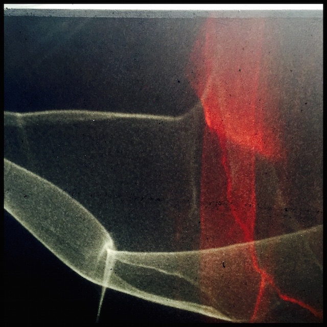 Evening sunlight reflected from car chrome and tail lights onto concrete wall