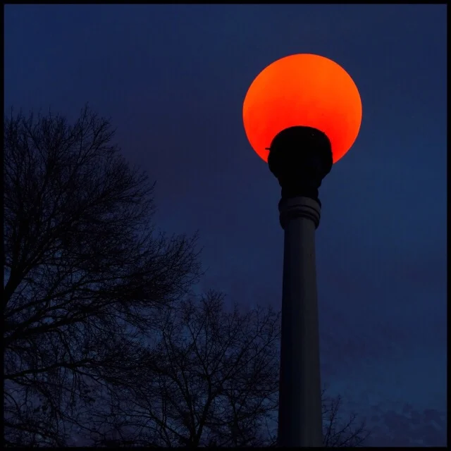Public fire alarm globe and stanchion against evening sky
