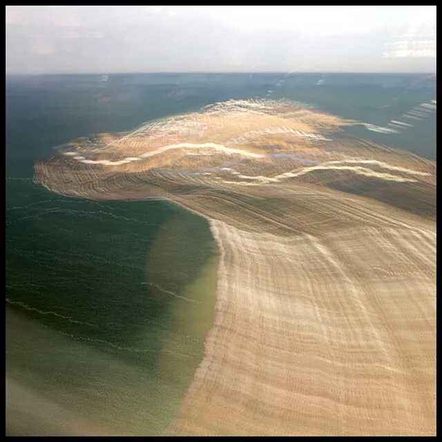 Peninsula seen from ascending plane, smudged as a sandy wave by slow shutter