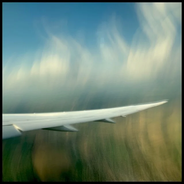 Fields, wing, clouds, minutes after take-off, slow shutter