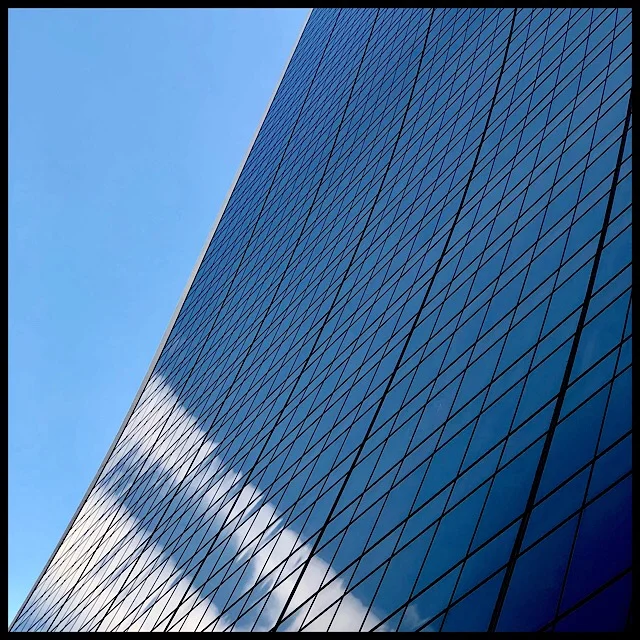 Curving facade reflecting two straight clouds