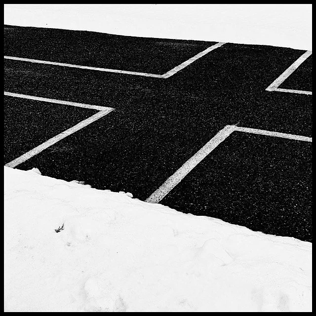 Four parking space markers between two banks of snow