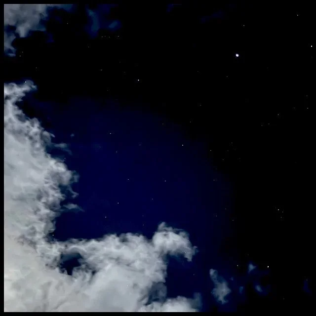 Starry night sky with moonlit clouds