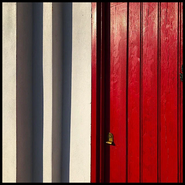White wall, red door, shadow-striped