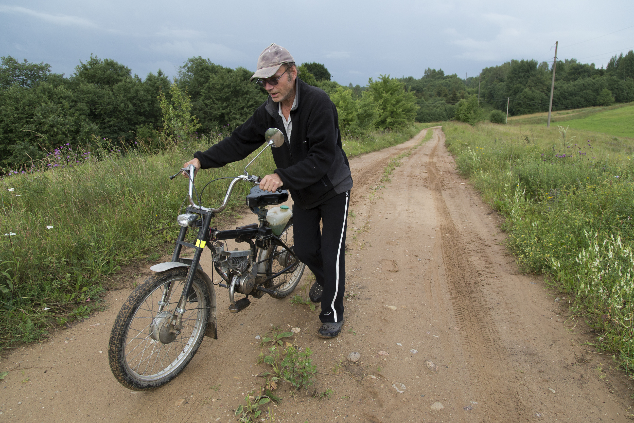 In need of repairs, my father pushes his motorcycle up a hill. "I ride it to town when I have work. I did a lot of work on it," said my father. On a couple occasions, my father has showed me photos on his phone of cars and motorcycles that he admires.