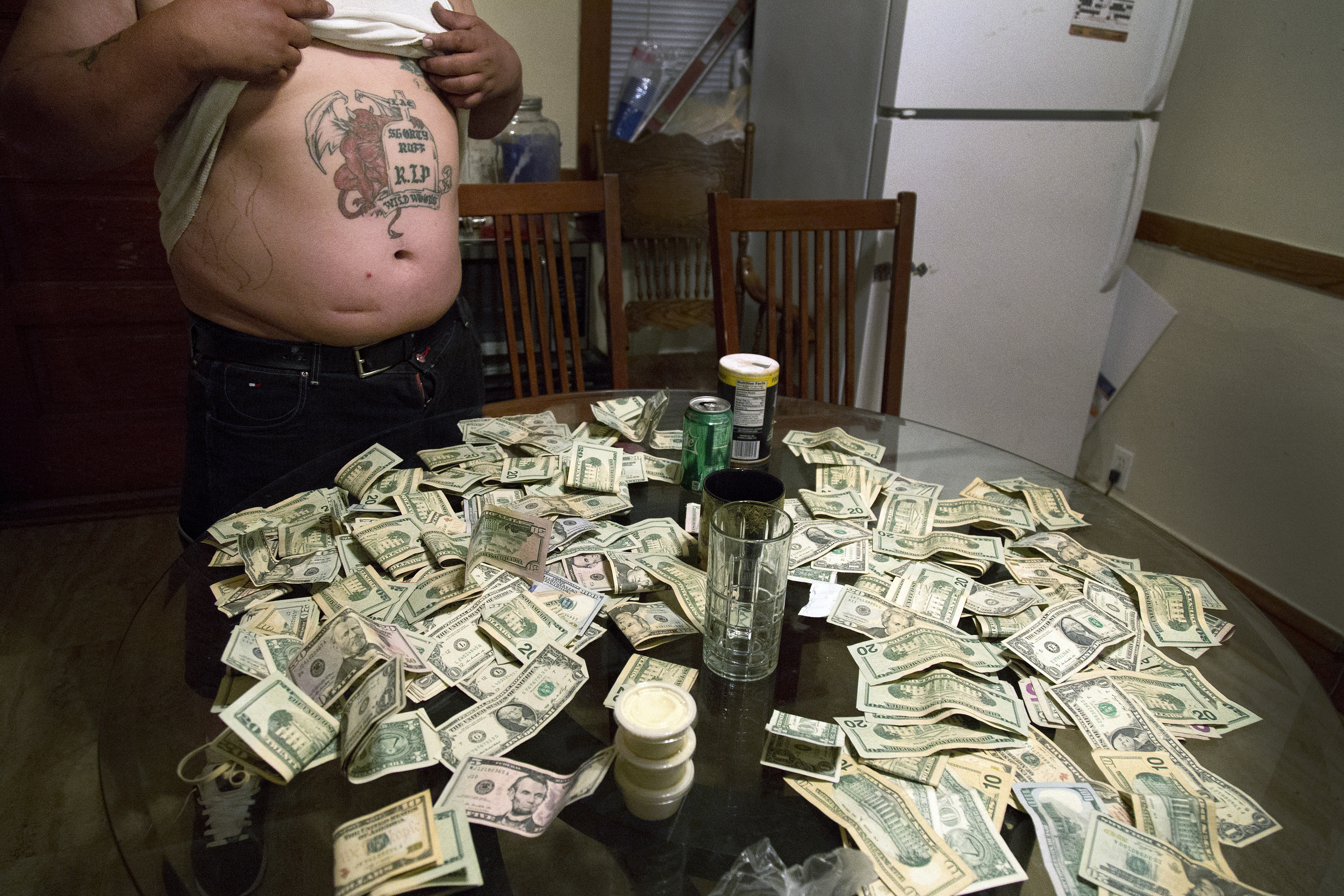 (Name withheld) exhibits money from selling drugs before giving half to his son on July 4, 2015, in Chicago. “My children get good grades, are athletes, and are going into the military. They’re not like me." He is on federal parole.