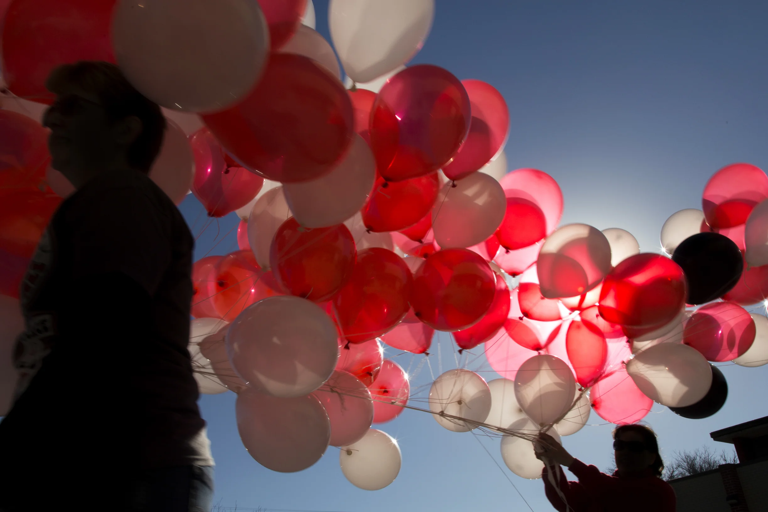 Volunteers carry balloons from inside the school to the football field.