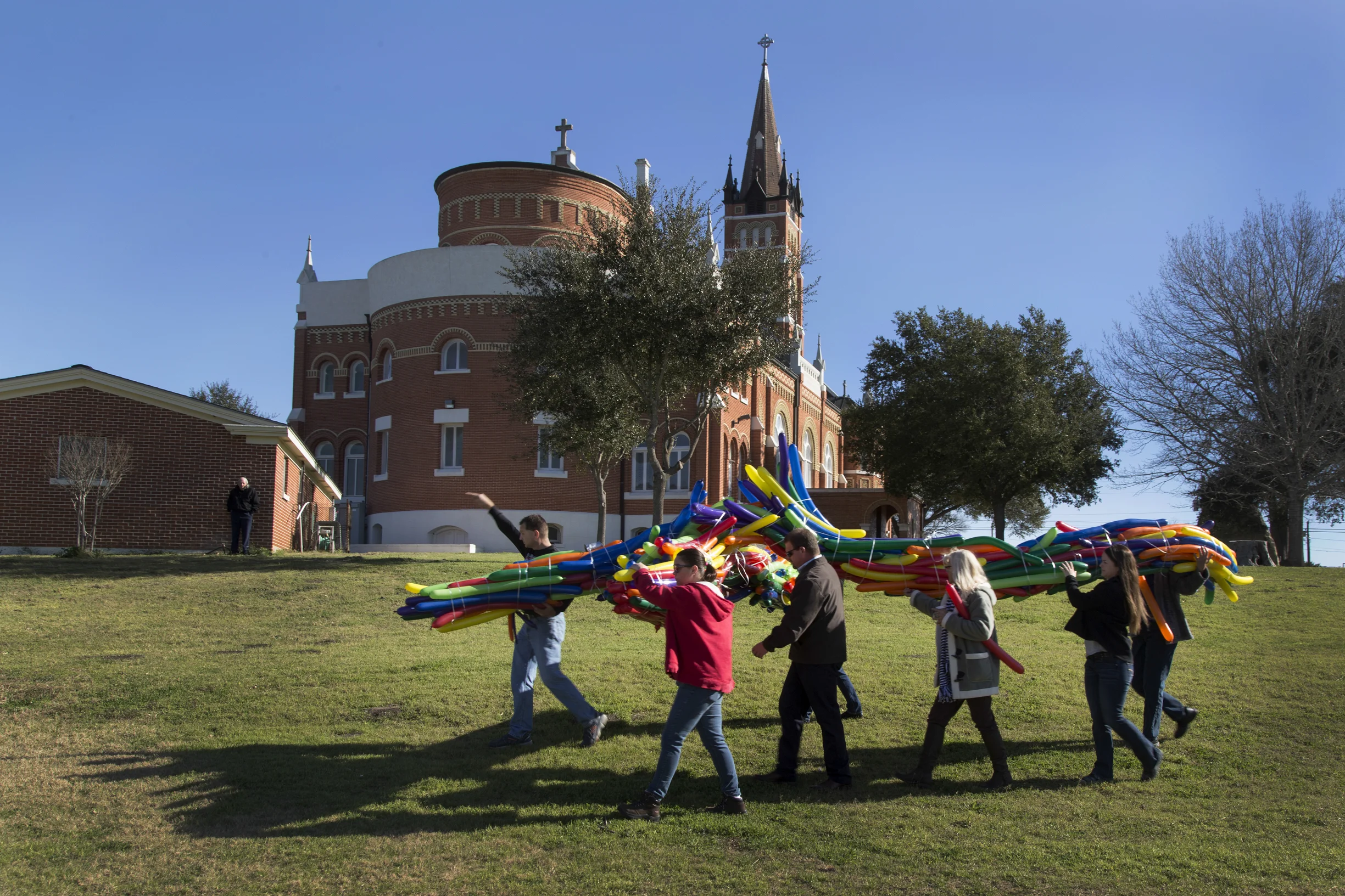 A cross made up of long, thin balloons is carried past the church to be released with hundreds of smaller ones. Larger ballons filled with helium were tied to the cross before its release.