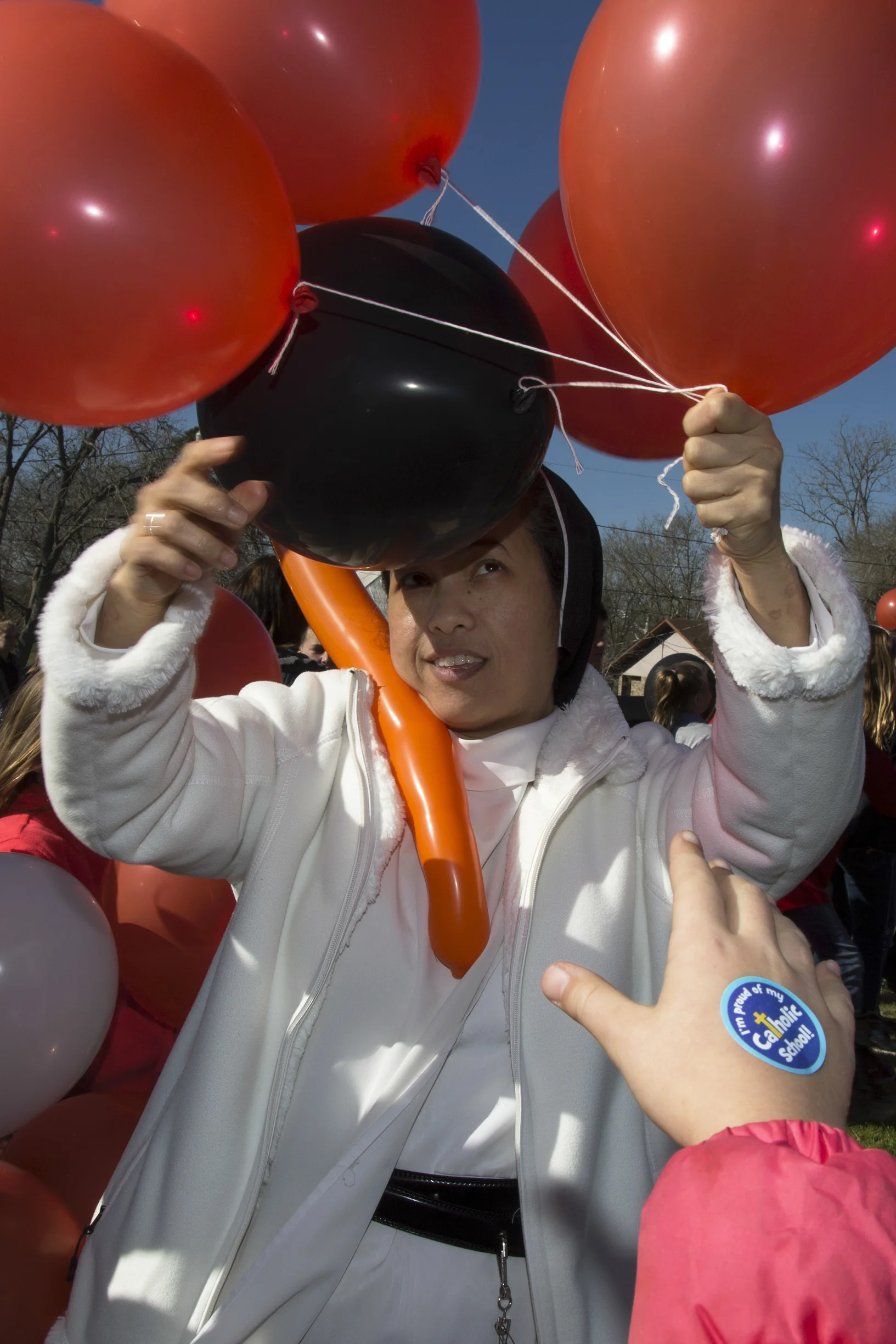 Sister Maria Raphael hands balloons to students of Shiner Catholic School.