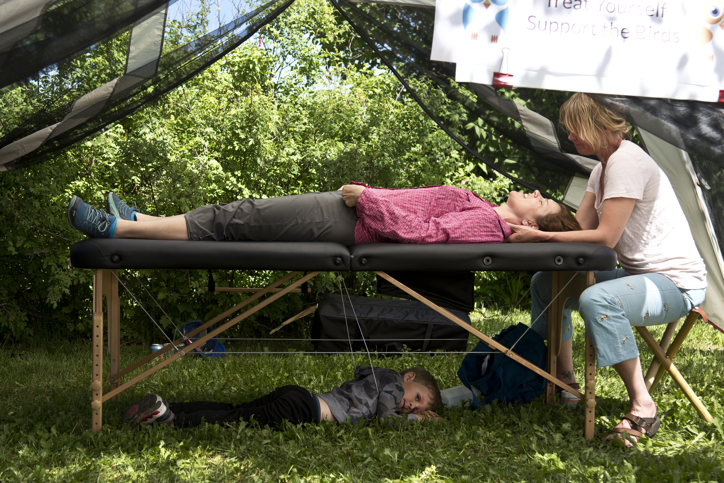 Kershaw Finlay, 4, lies on the ground while his mother, Rebecca Huntington, receives a massage during RaptorFest on Sunday, June 19, 2016, at the historic Hardeman Barns in Wilson, Wyo.