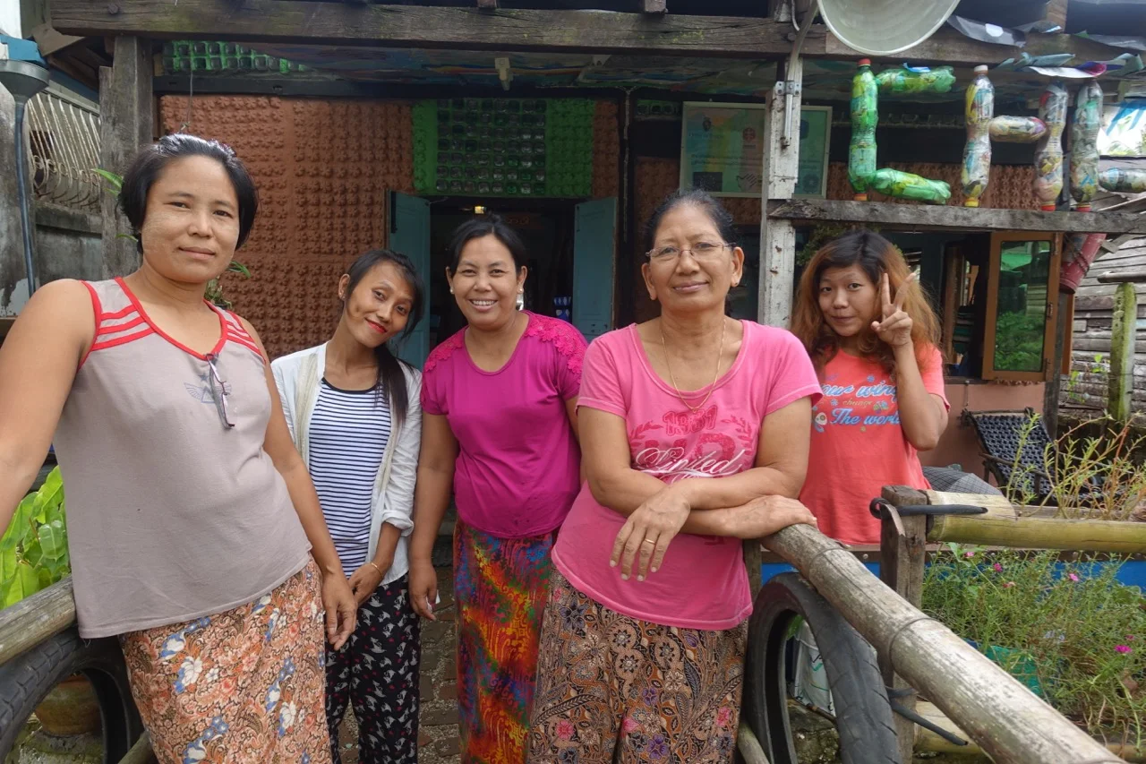 Meet the ChuChu makers! ChuChu is a workshop space located in Dala Township, on the southern bank of the Yangon River, across from downtown Yangon. Six families work there together and sell their crafts to locals and tourists visiting from Yangon. They work with recycled plastics to create new fabric, which they use to make purses, bags, and household goods. The artisans often work in the middle of the night when electricity is more reliable. Each member is a designer and their work continually evolves. As they forge new creations, new ideas are born and explored. This group of designers all consult one another in their work; each person has a voice in business decisions from designs to strategy. Together, they set the prices for their crafts and ensure their business is sustainable. The ChuChu workshop space is also made of recycled goods.