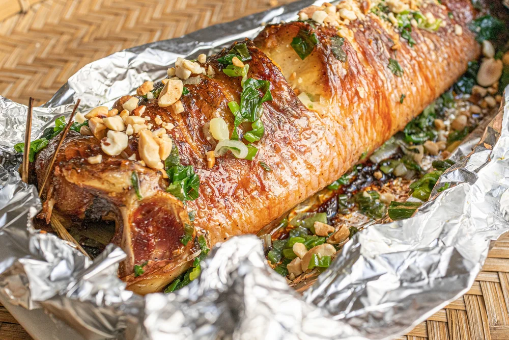 Whole grilled or baked snakehead fish (Cá Lóc Nướng) served on a bamboo platter