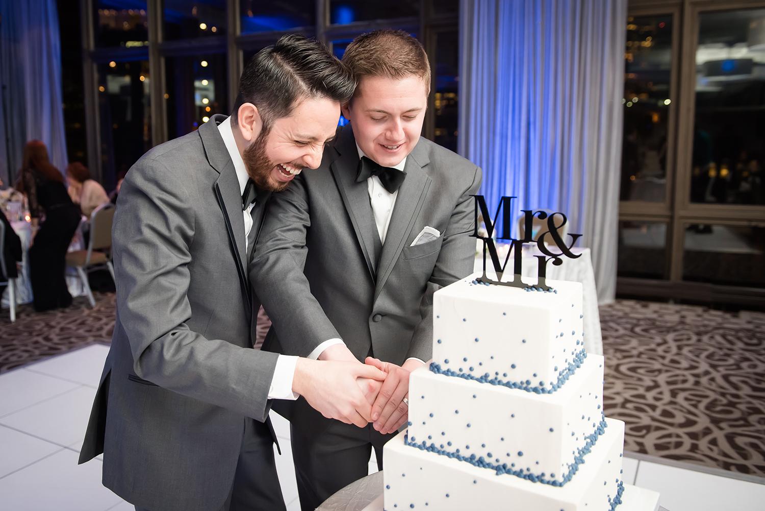 two grooms cutting cake