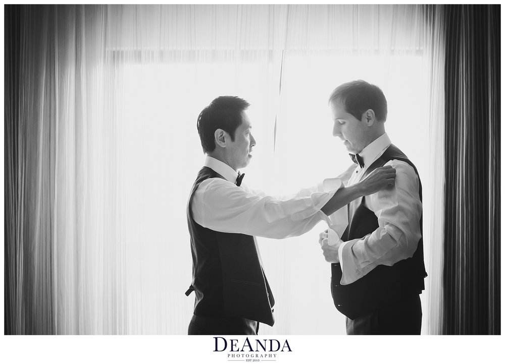 grooms helping each other get ready together in black and white in chicago