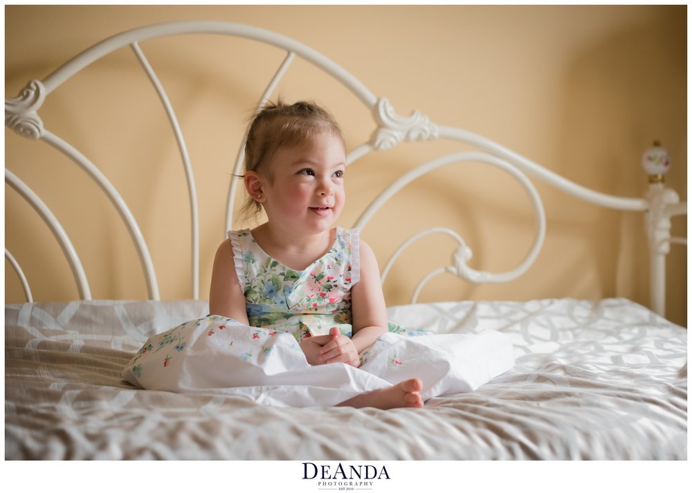 little girl sitting on bed for 2 year old portraits