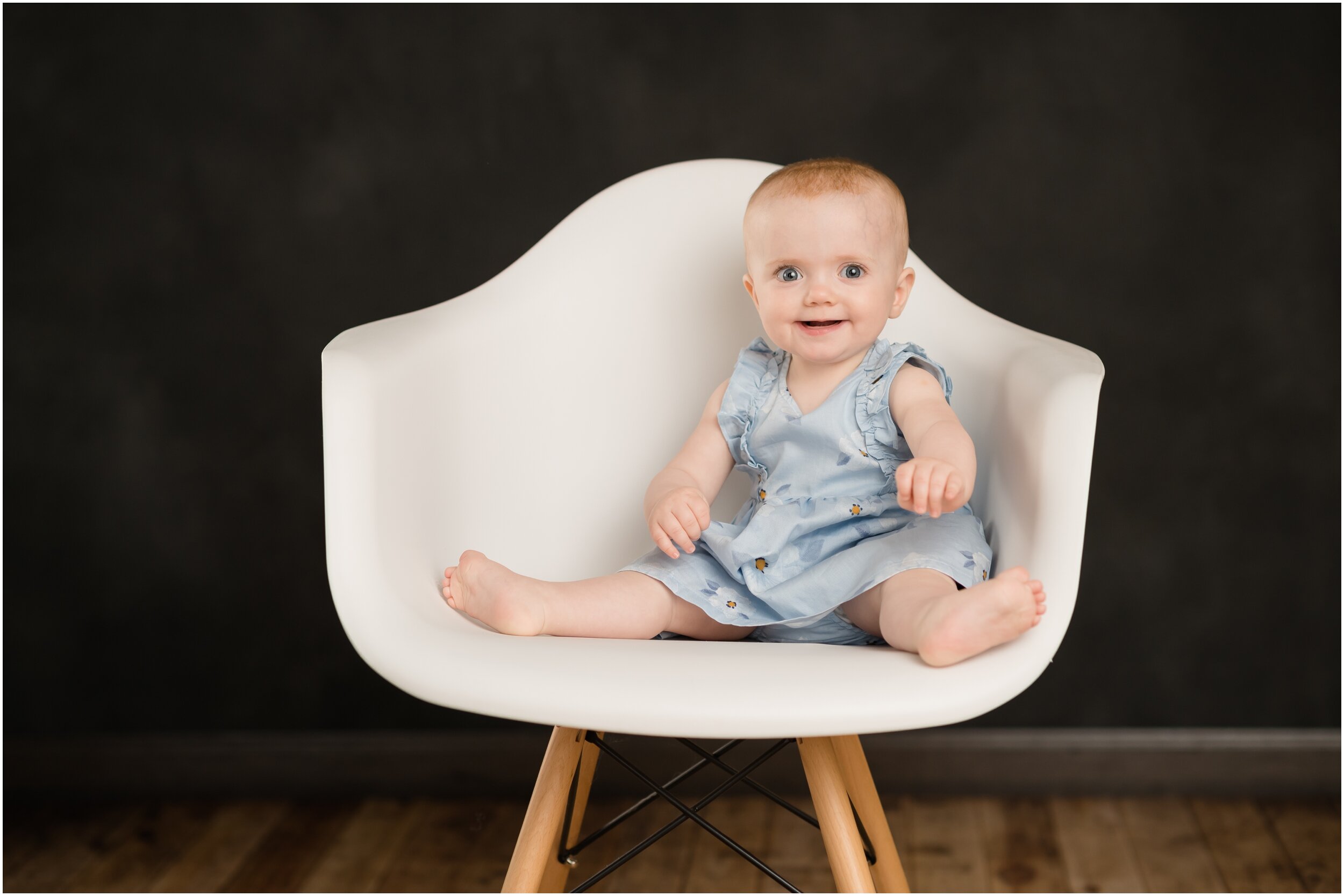 baby in blue dress in white mod chair
