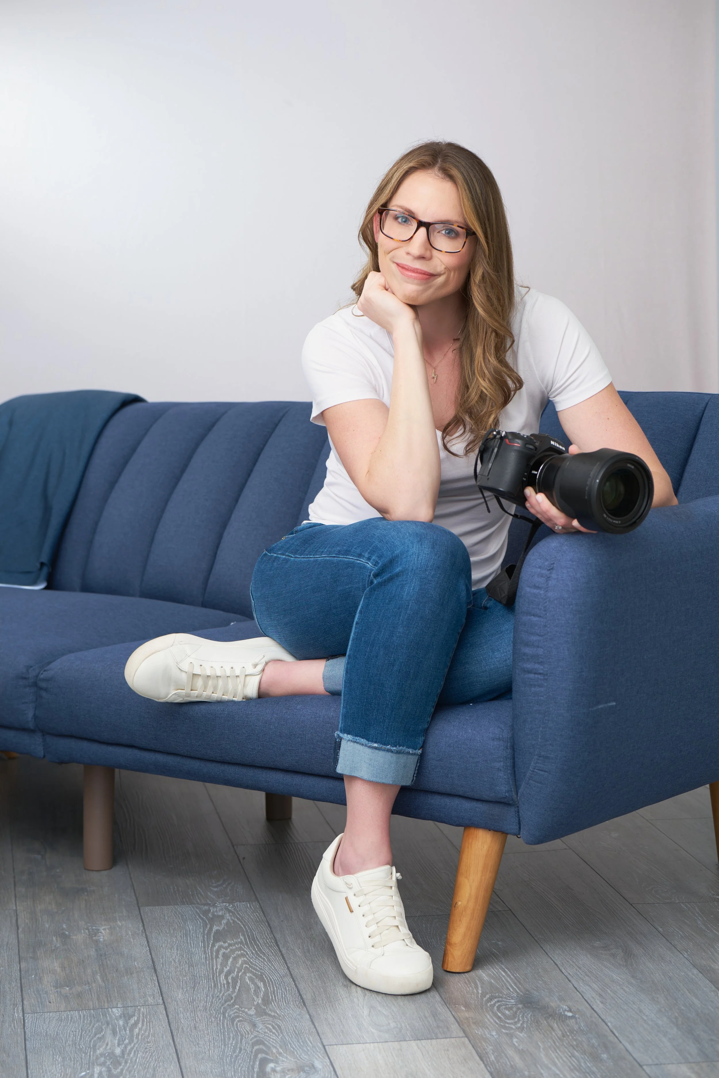 headshot of carol deanda on a blue couch with camera