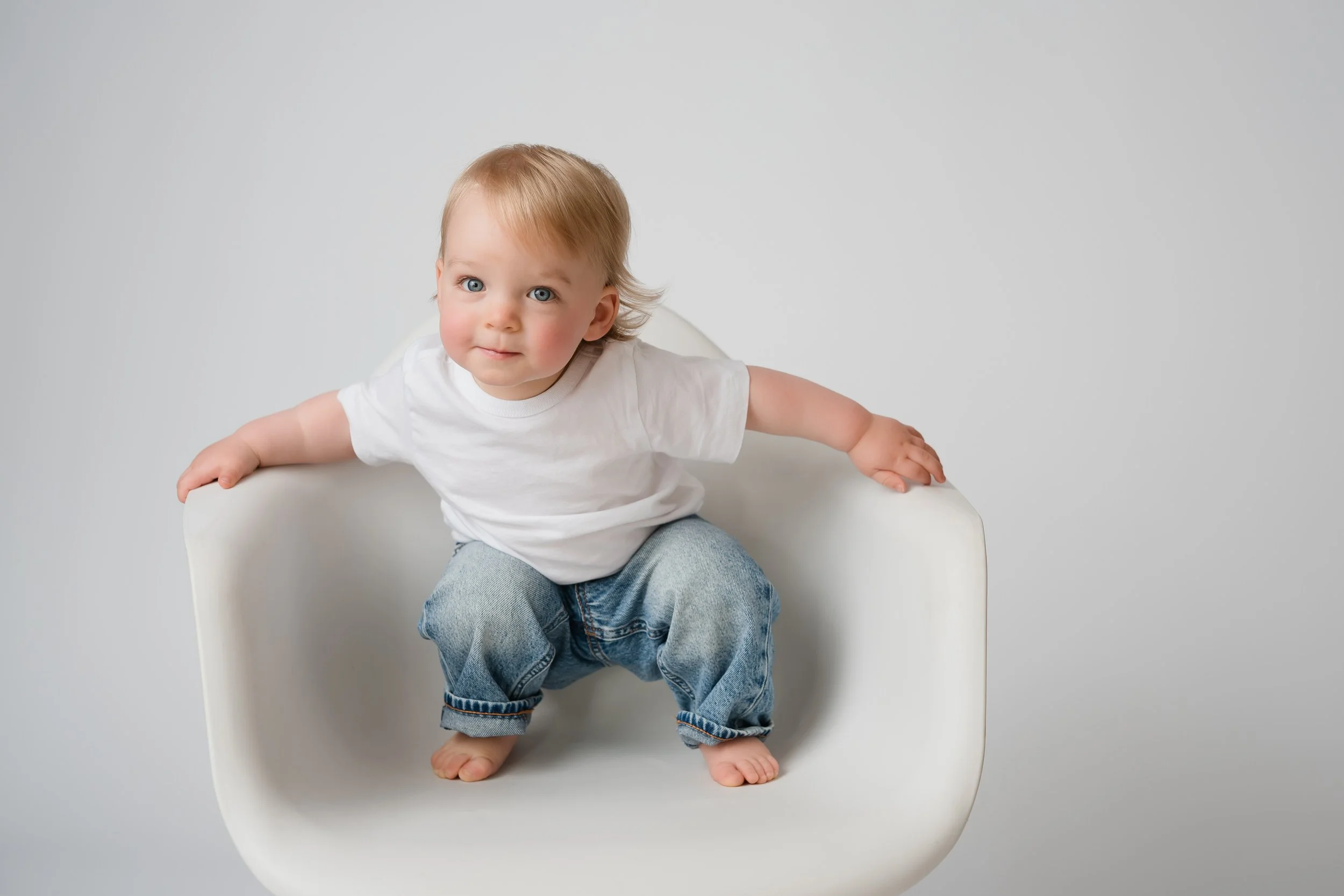 1 year old in white chair for 1 year photos at photo studio