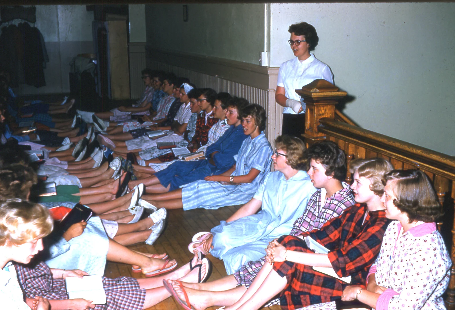 A common sight in evenings around the Castle, night gatherings for communication, prayer, and singing have been an ongoing tradition at Hillcrest. Here, Janet (Monson) Aasby, leads the girls in a chorus during her time as an assistant dean.