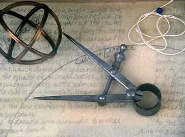 metalsmith divider tool pointing to a sphere on top of aged paper