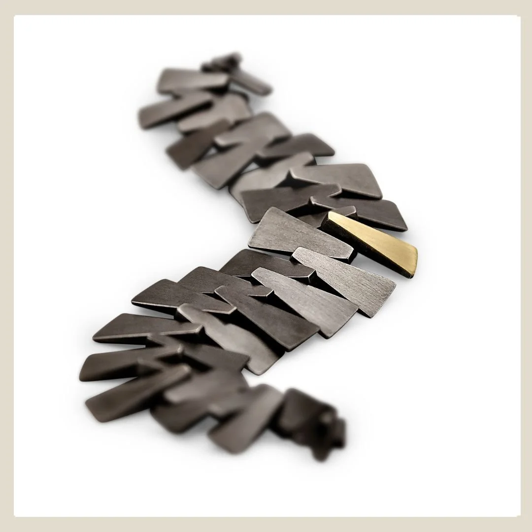 Showcasing Eatmetal's black patina sterling silver bracelet with gold link.