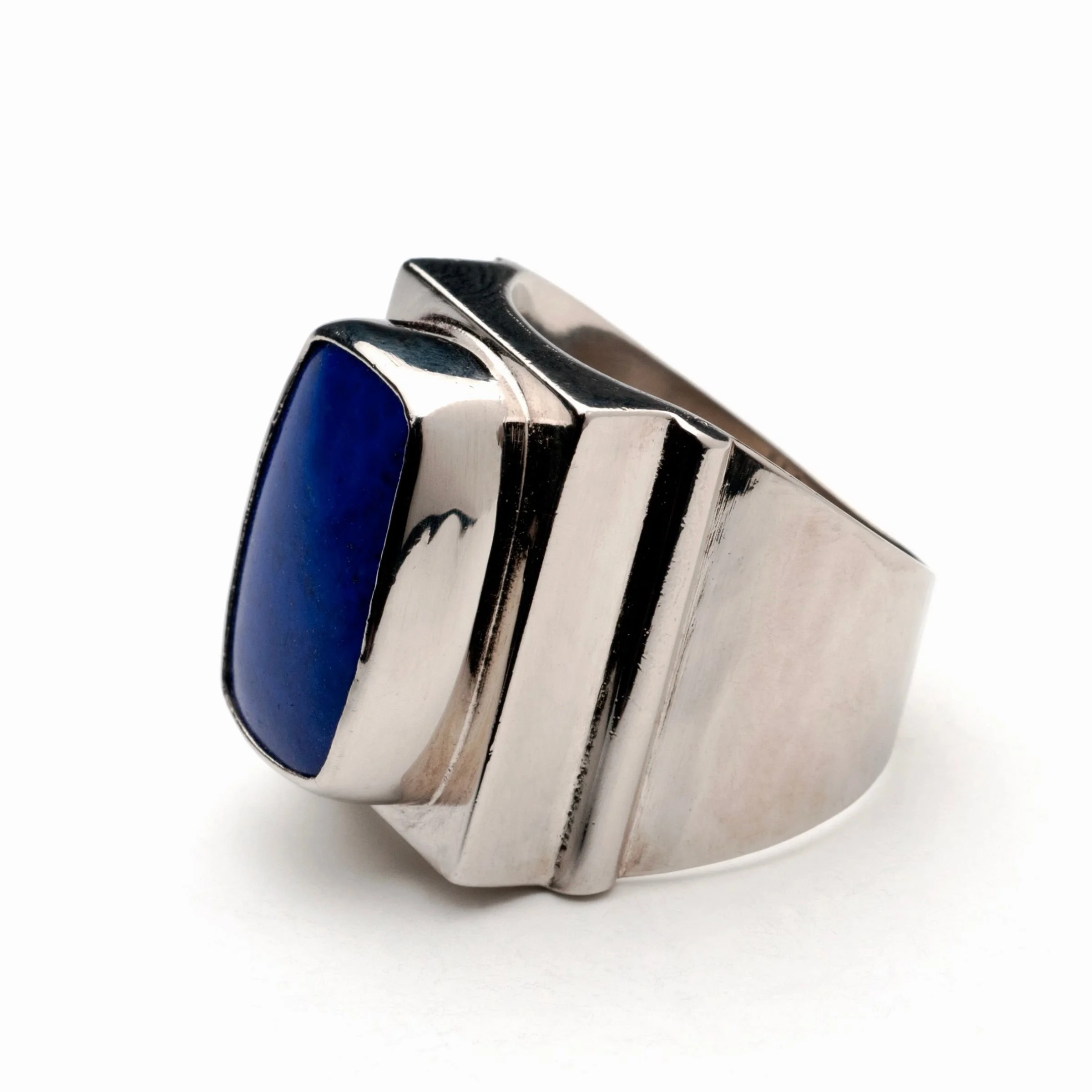 Bold sterling silver signet ring showcasing a prominent cushion-cut blue lapis lazuli gemstone flush-set on a wide, chunky band with a modern grooved, architectural design