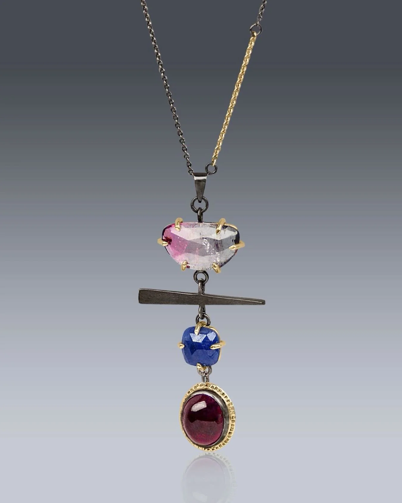 Walking Fern Leaf Necklace

Handmade statement piece featuring rose-cut graduated tourmaline and blue sapphire prong set in 14k gold. A pink cabochon is framed in textured 14k gold halo, and a patinated silver forged bar.  Suspended from a sterling s
