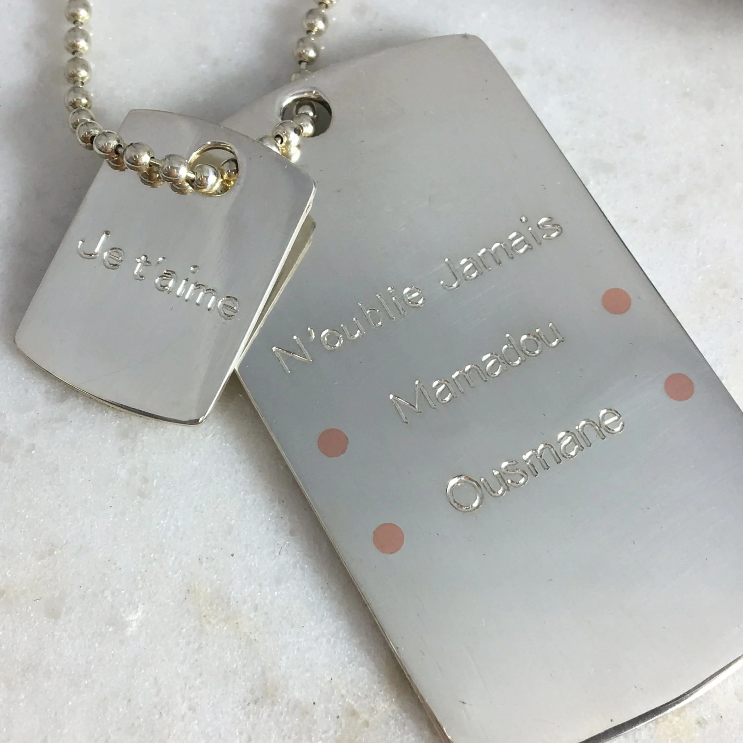 Personalized sterling silver double dog tag necklace featuring custom french engraving and copper rivets on the larger tag