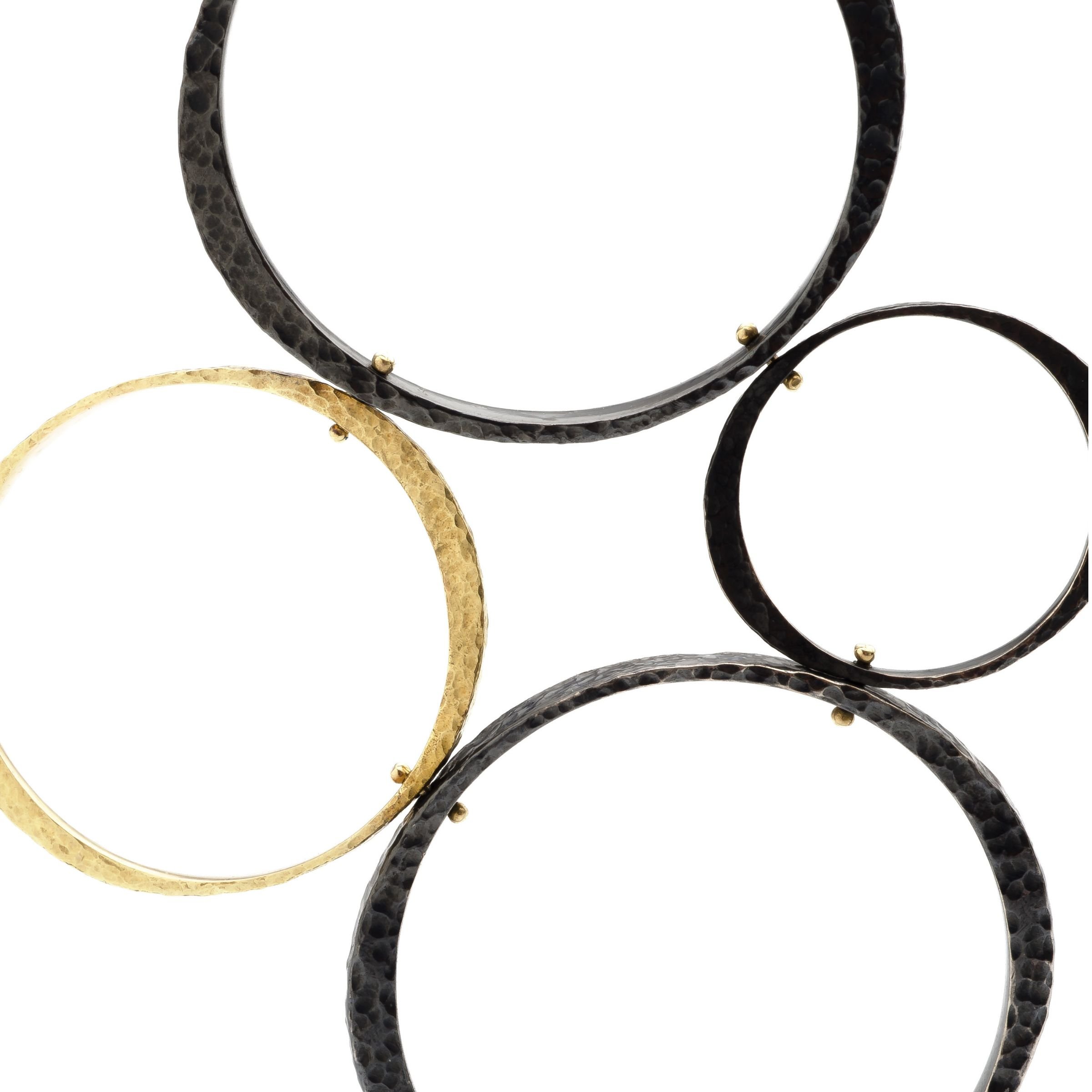 Close-up of four interconnected circle pendant featuring patinated sterling silver and 18k gold circles by EatMetal in Hoboken, NJ