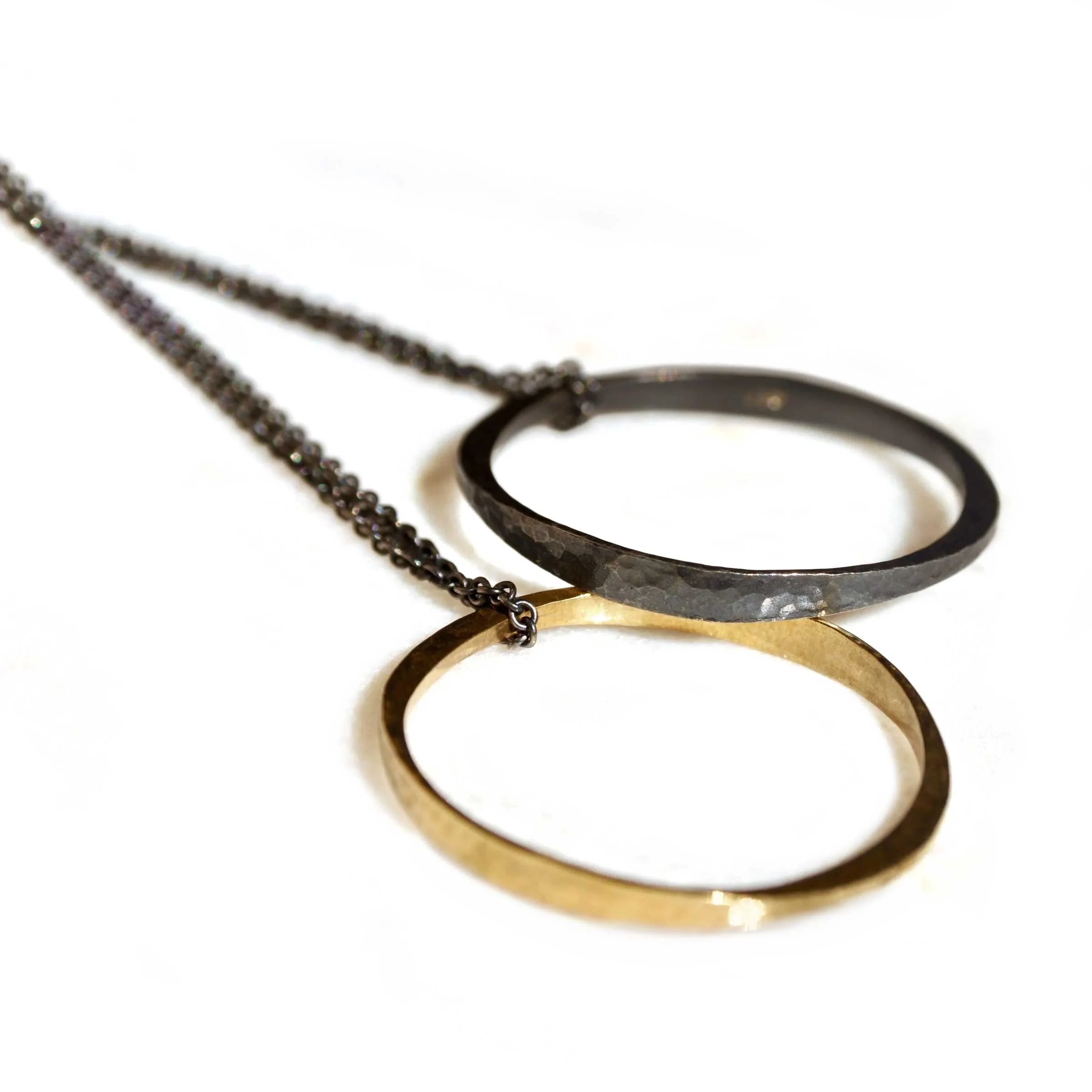 Angled close-up view highlighting the hand-hammered finish and contrast between the patinated sterling silver and gold rings.