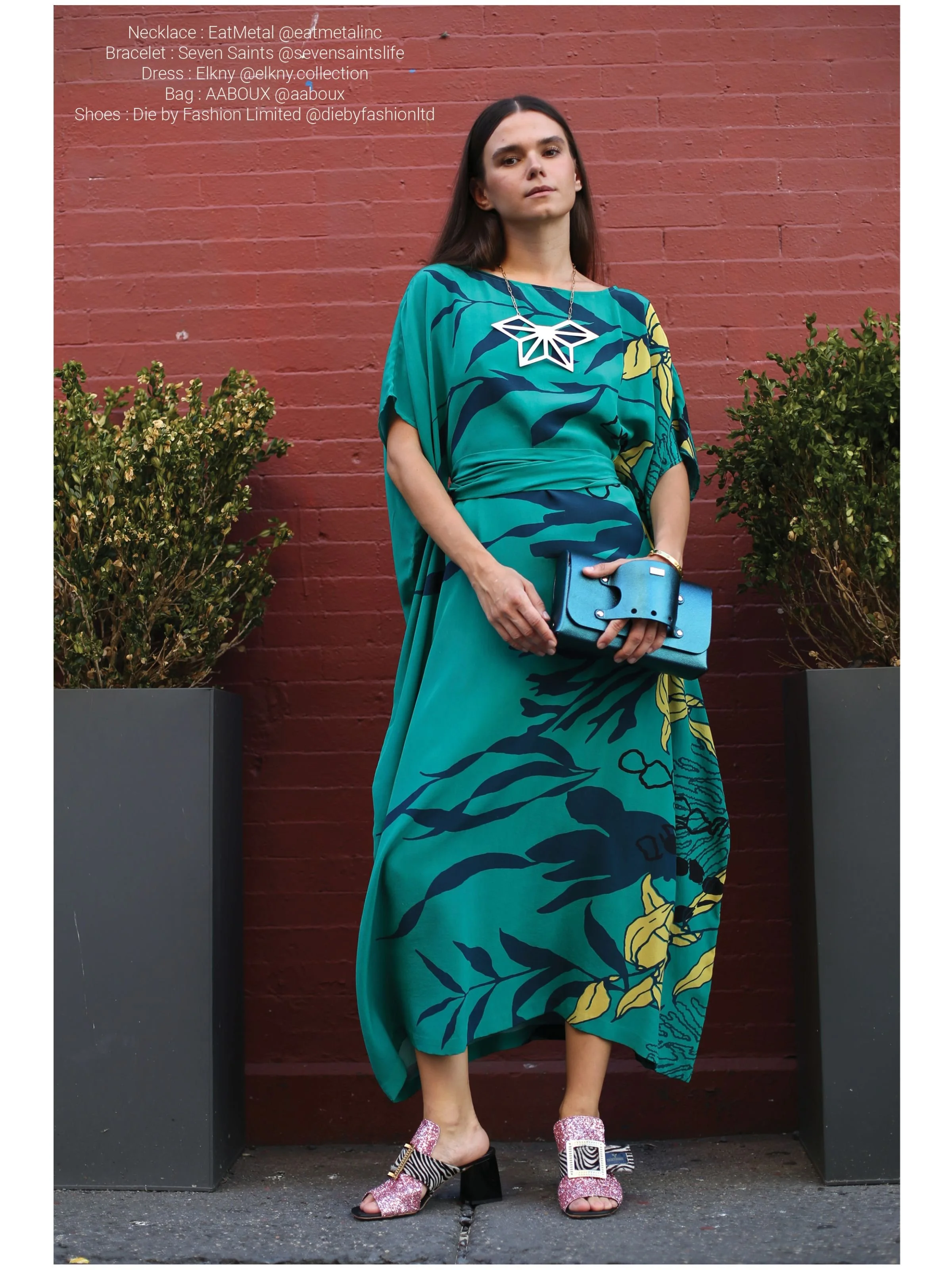 22 karat gold overly brass Asanoha Necklace on Malvie Magazine model also wearing green and blue dress against a red brick wall