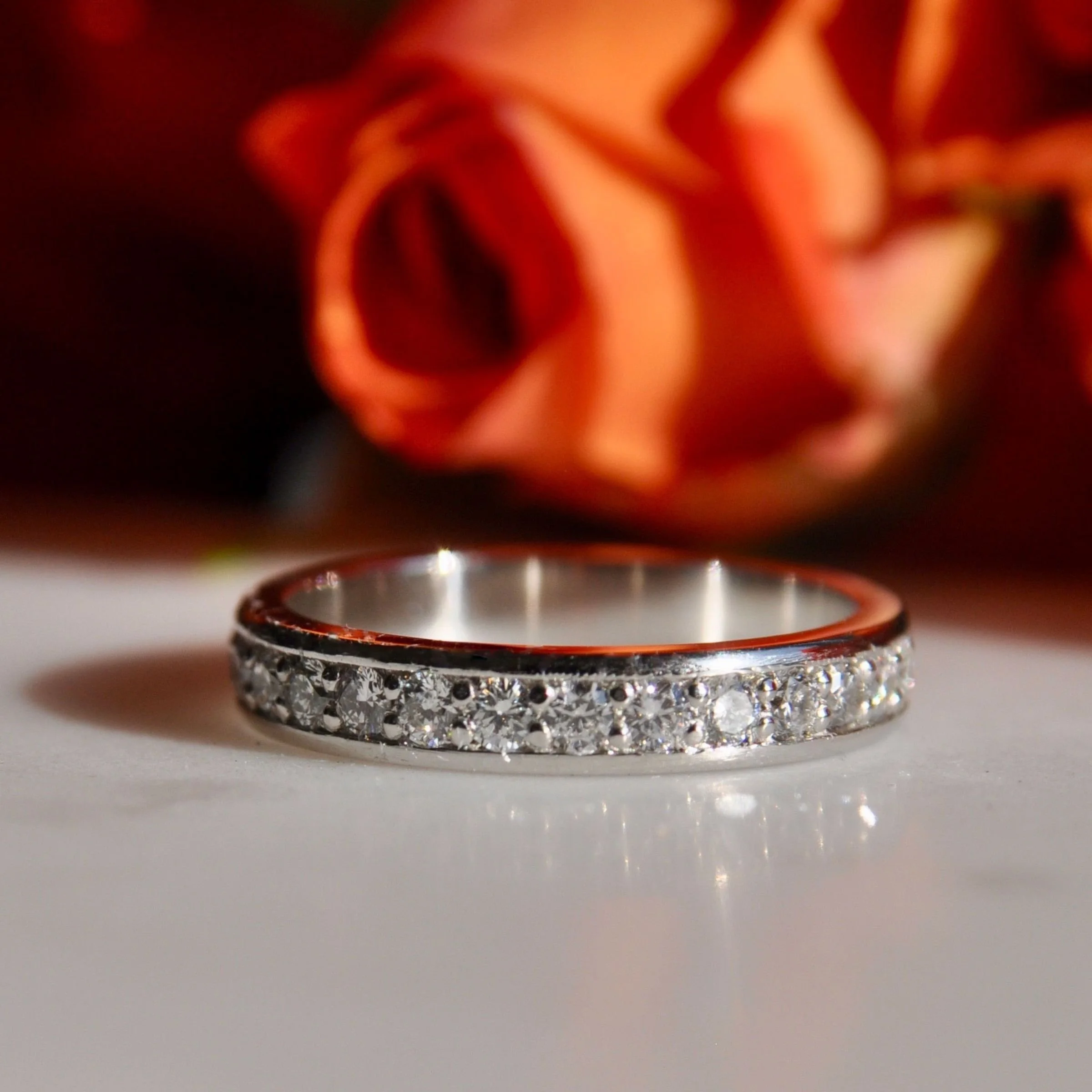 A contemporary platinum diamond eternity wedding band featuring a channel-set border with round brilliant cut pavé diamonds