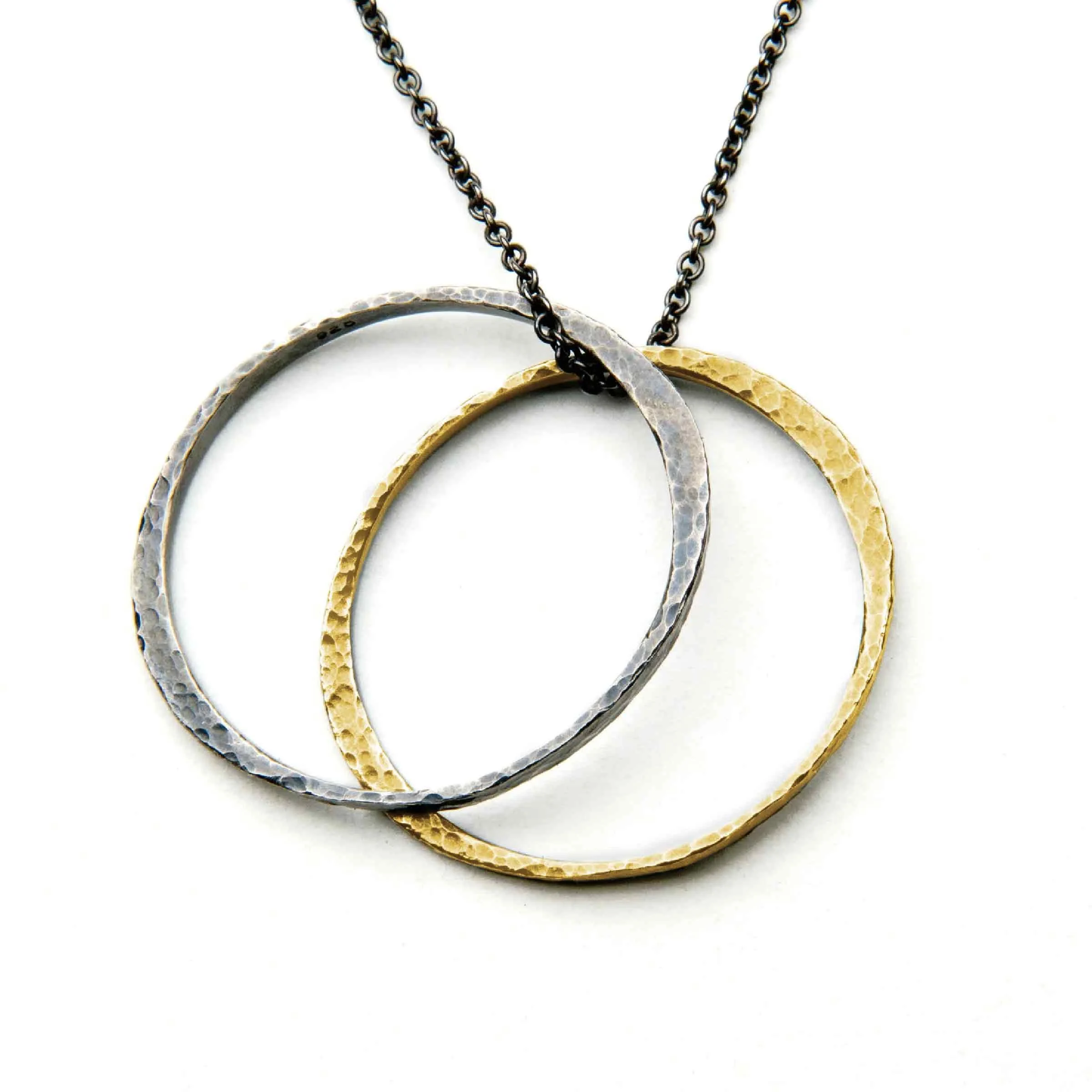 Detailed front close-up showing the hand-hammered texture of the patinated sterling silver and gold crossover circles.