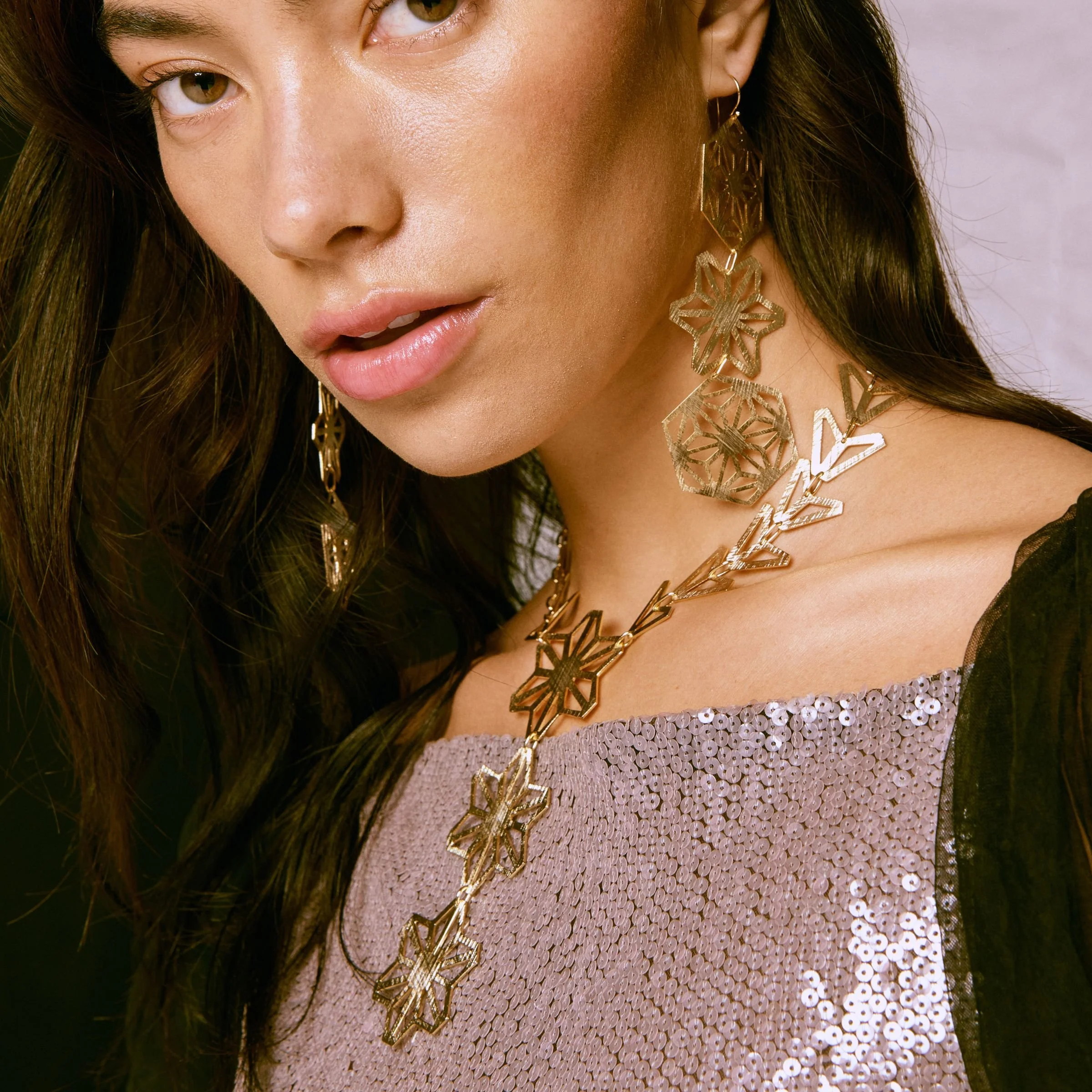 Close-up of model wearing the architectural Asanoha triple star statement necklace highlighting the geometric pattern and chevron chain.