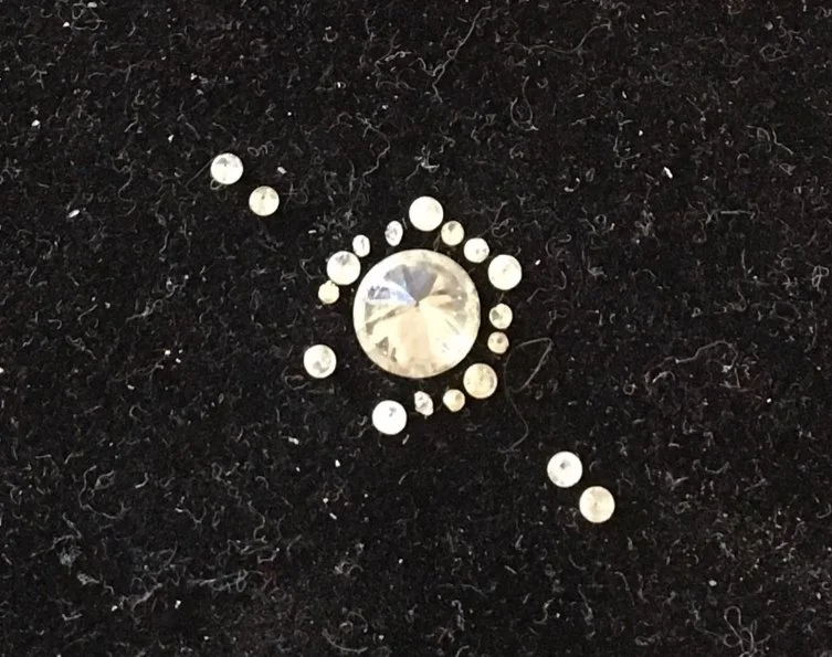 the highest quality gemstones and diamonds against a black felt are sourced exclusively thru certified gemologists to meet standards in excellence and authenticity