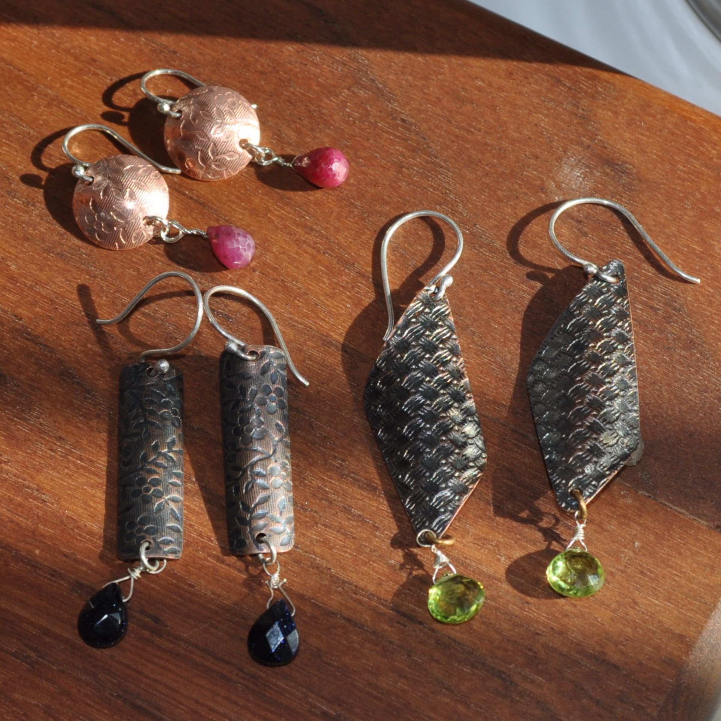 Custom embossed roll-printed sterling silver earrings with wire-wrapped semi-precious stone charms made in a DIY jewelry workshop