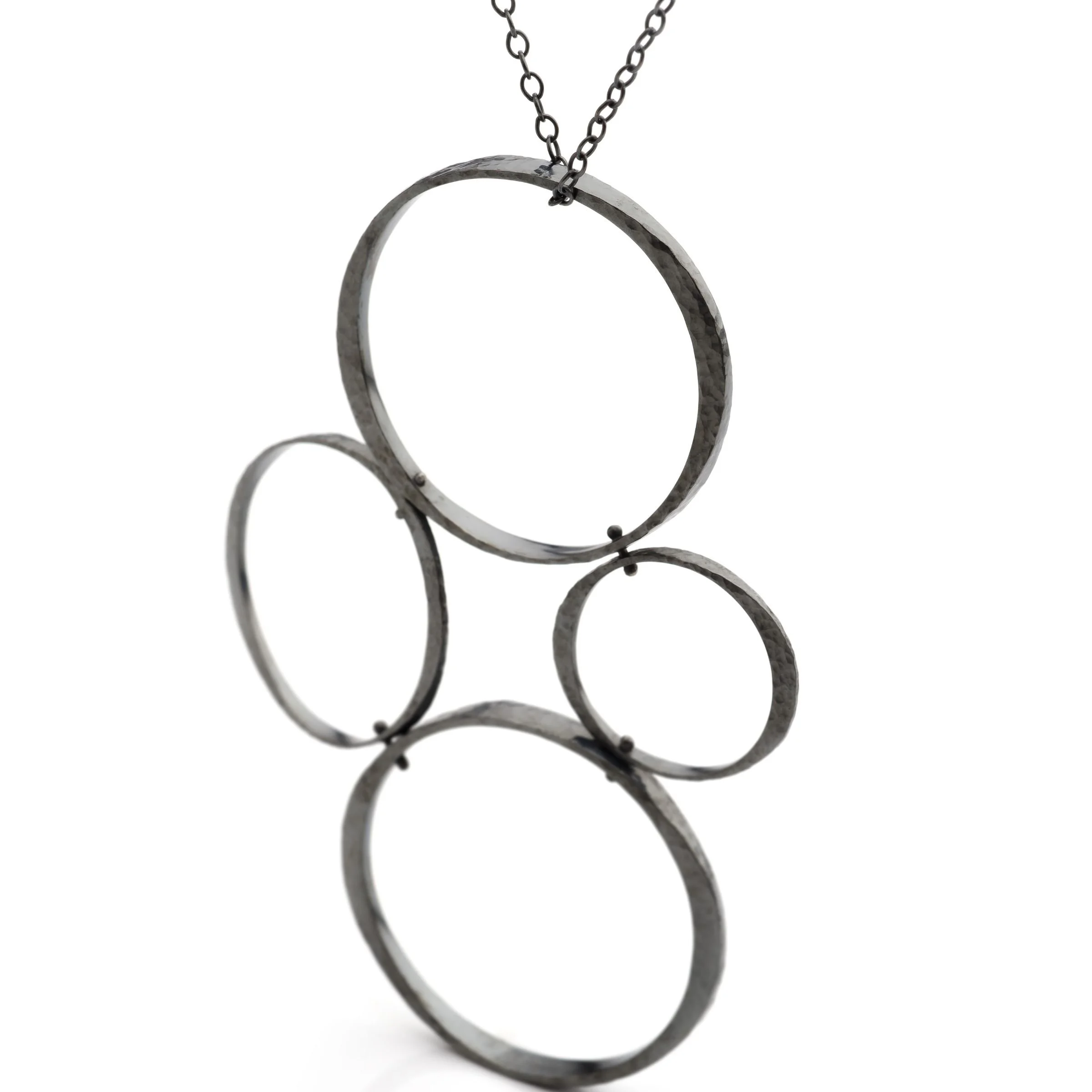 Patinated sterling silver Tetrad Circle pendant necklace displaying a dark oxidized finish and asymmetrical four-circle design.