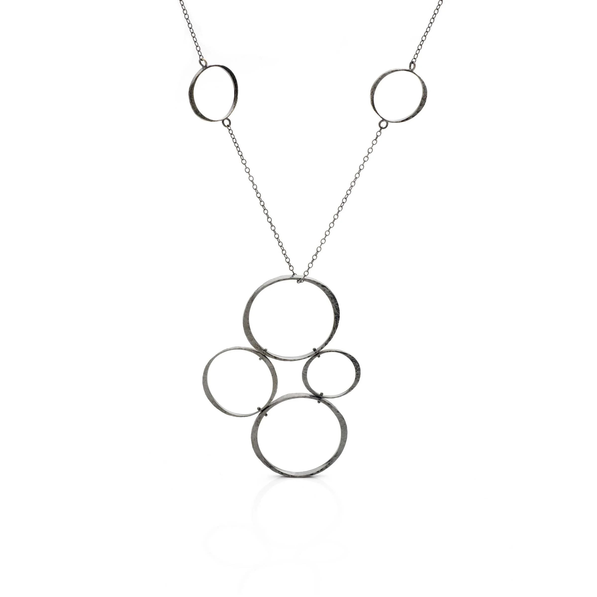 Patinated sterling silver Tetrad Circle pendant necklace displaying a dark oxidized finish and asymmetrical four-circle design.