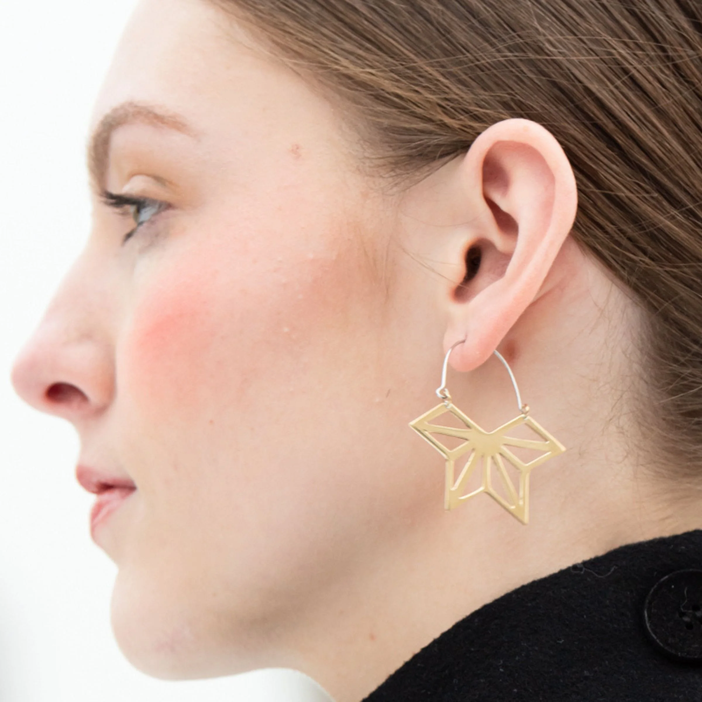 Model wearing the EatMetal Hemi-Asanoha geometric hoop earrings in 22k gold overlay brass featuring a half-star openwork pendant and sterling silver hoop ear wire.