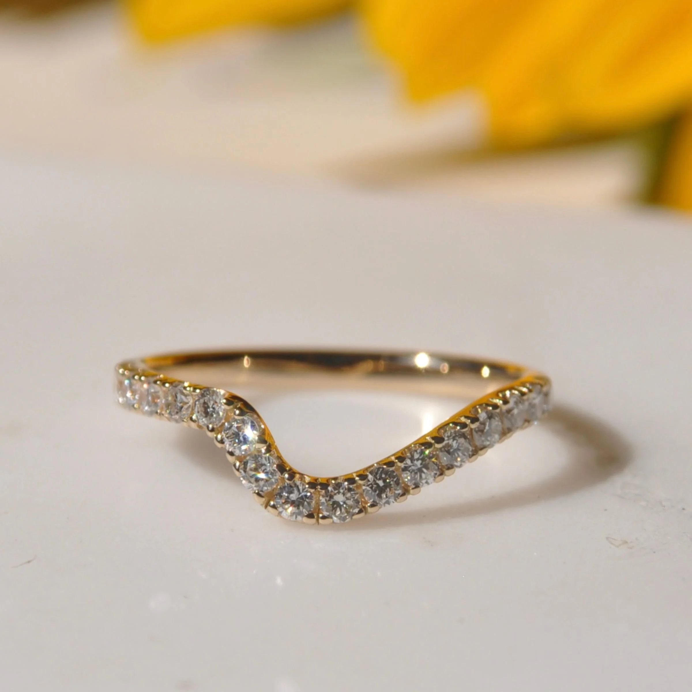 A modern 14k yellow gold curved / chevron wedding ring featuring a contoured pavé-set  with sparkling round brilliant cut diamonds
