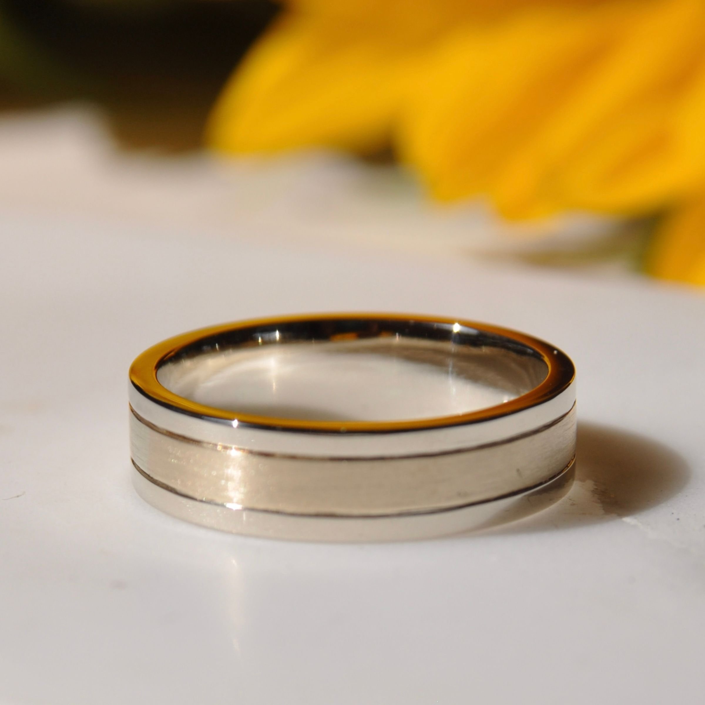 A bimetal of 14k white and yellow gold wedding band with a brushed matte center section and polished grooved borders.